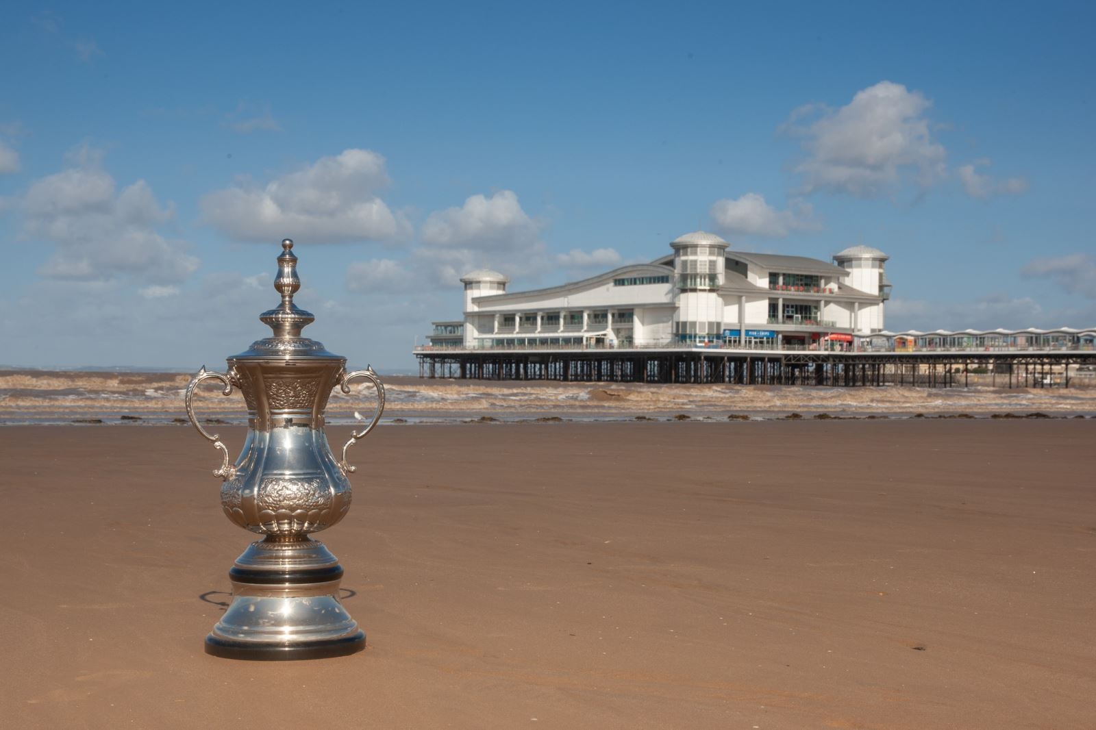 A replica FA Cup on the sand at Weston-super-Mare beach with the Grand Pier in the background